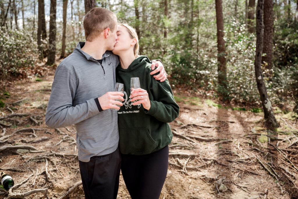 Newly engaged couple, Jake and Mallory, embracing with the stunning cliffs of Red River Gorge in the background.