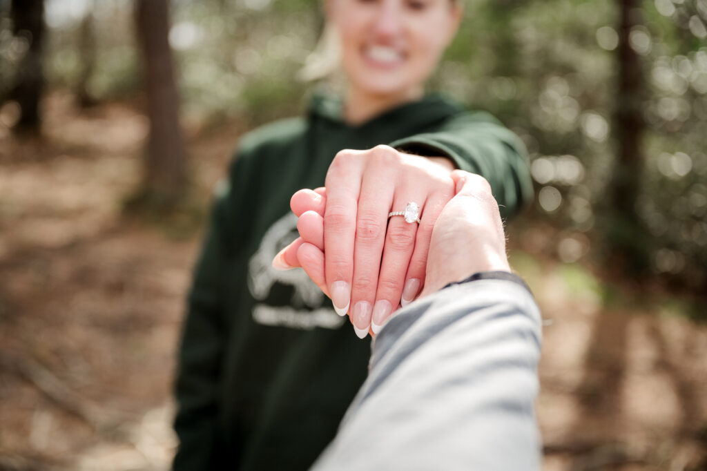 A sparkling engagement ring on Mallory’s hand, with freshly done nails and the natural backdrop of Red River Gorge