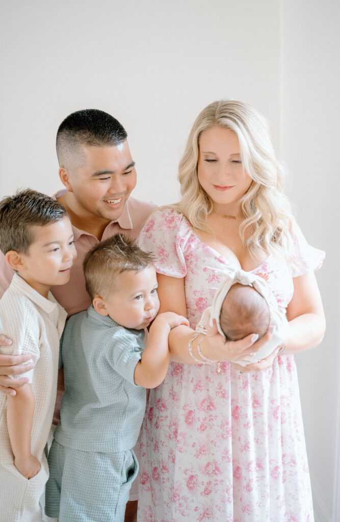 Big brothers smiling while holding their newborn baby sister during Lexington KY family session