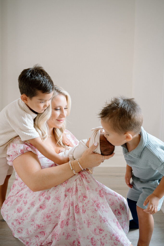 Big brothers smiling while holding their newborn baby sister during Lexington KY family session
