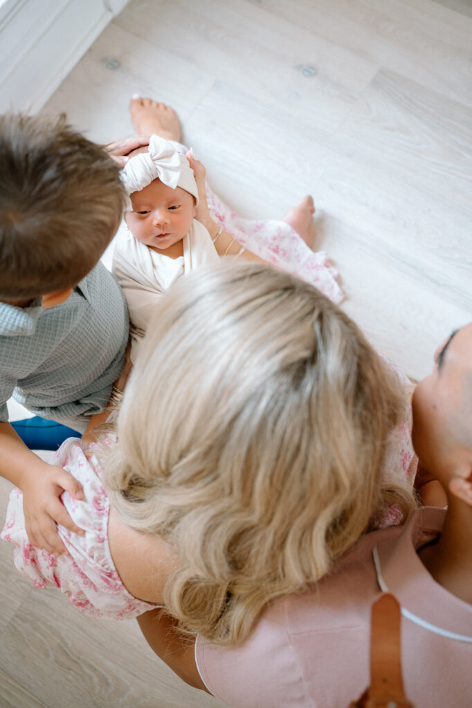 Big brothers smiling while holding their newborn baby sister during Lexington KY family session