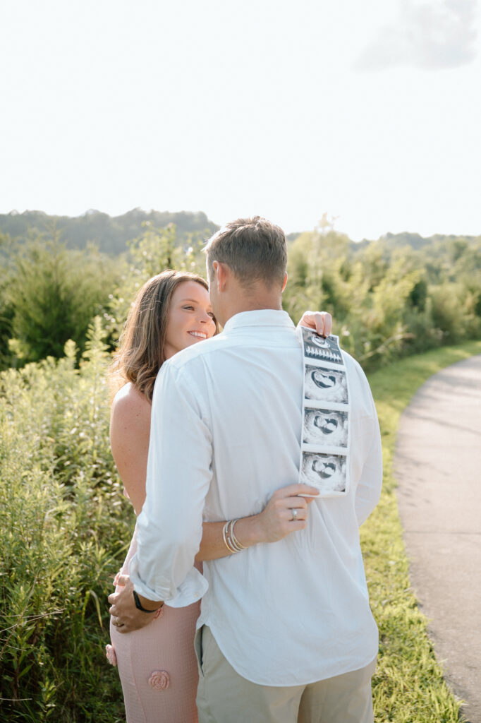 Pregnant couple smiling during pregnancy announcement photoshoot in Louisville KY