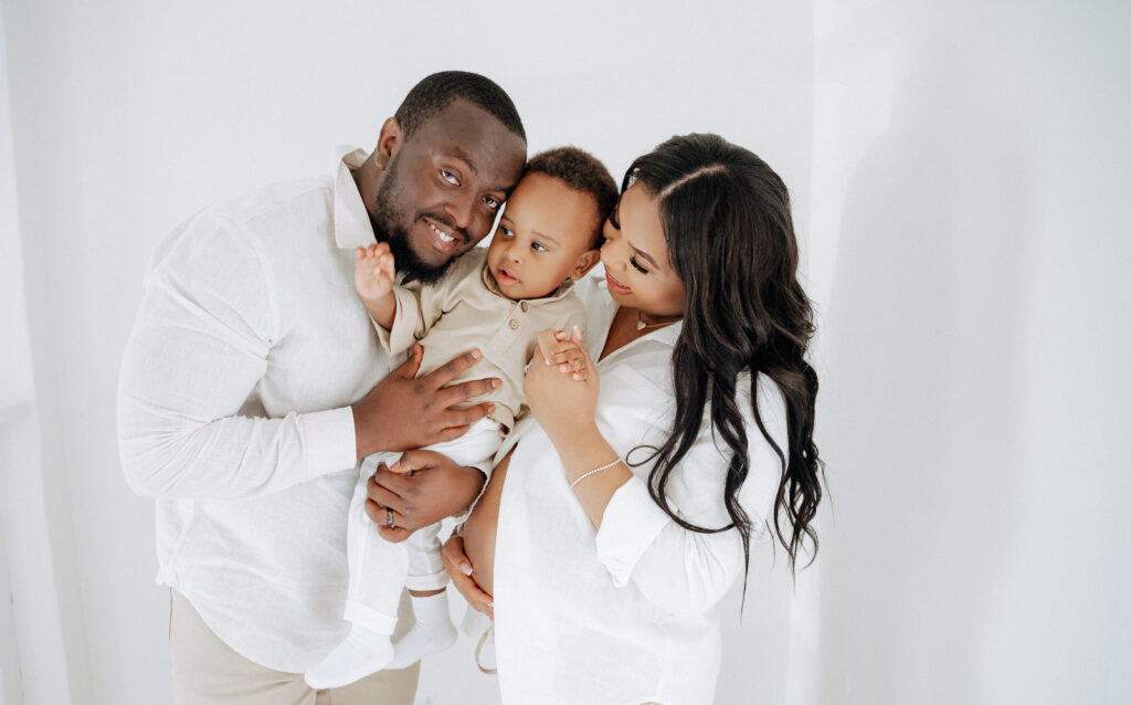 Toddler gently kissing pregnant mother’s belly during maternity session.
