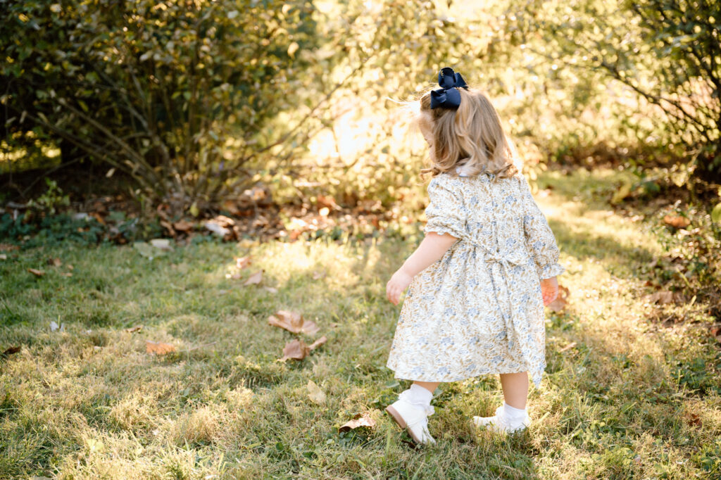 Parent and child walking on a leaf-covered path during fall mini session in Lexington