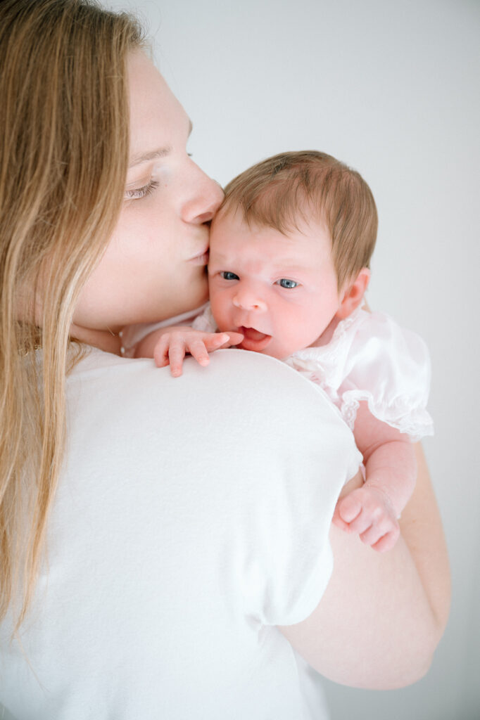 Newborn baby swaddled in a neutral blanket during a lifestyle photography session in a Lexington, KY studio.