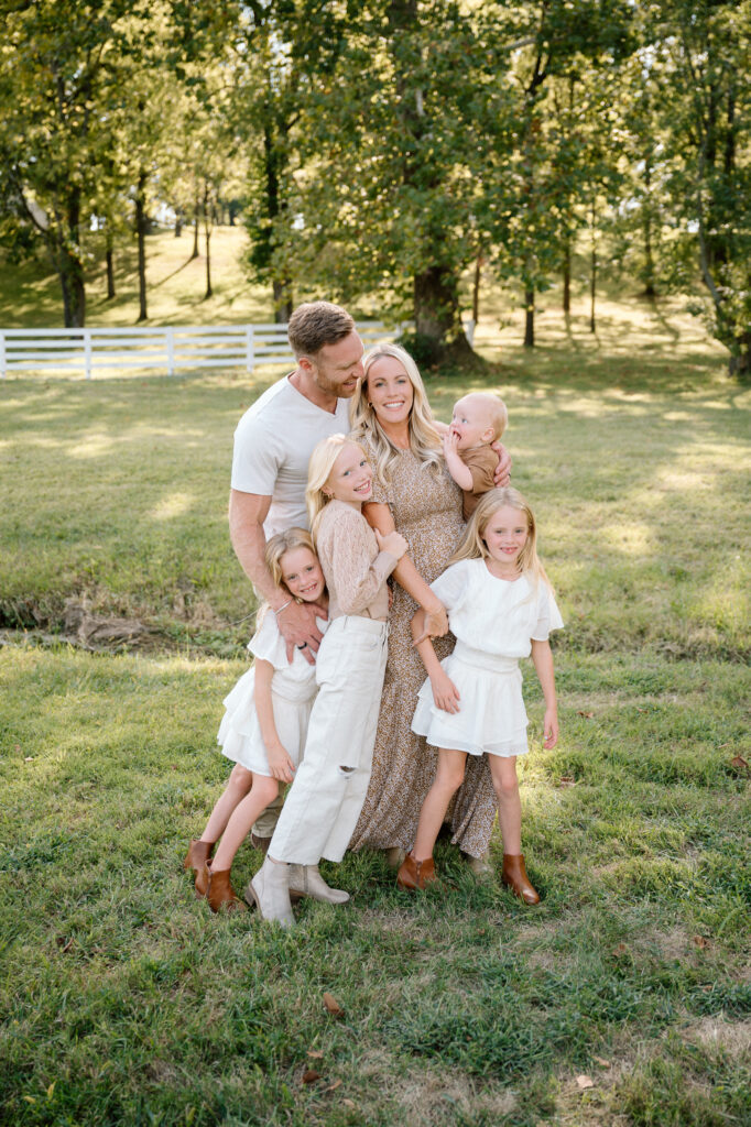 Family smiling during 2025 Kentucky fall mini session with warm golden leaves at Keeneland