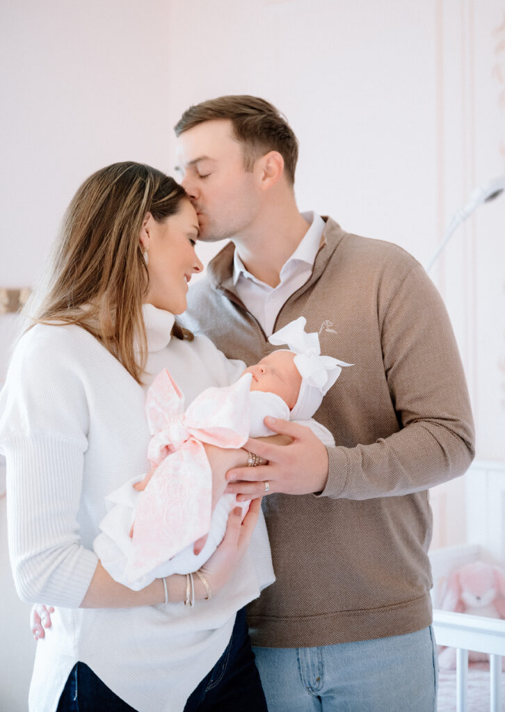with parents holding baby in natural window light.
